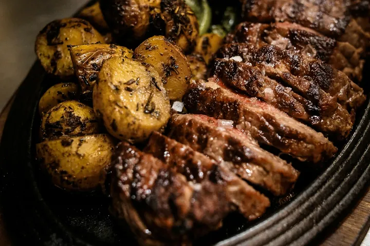 Aufgeschnittenes Fleisch mit gebratenen Kartoffeln und grünem Gemüse